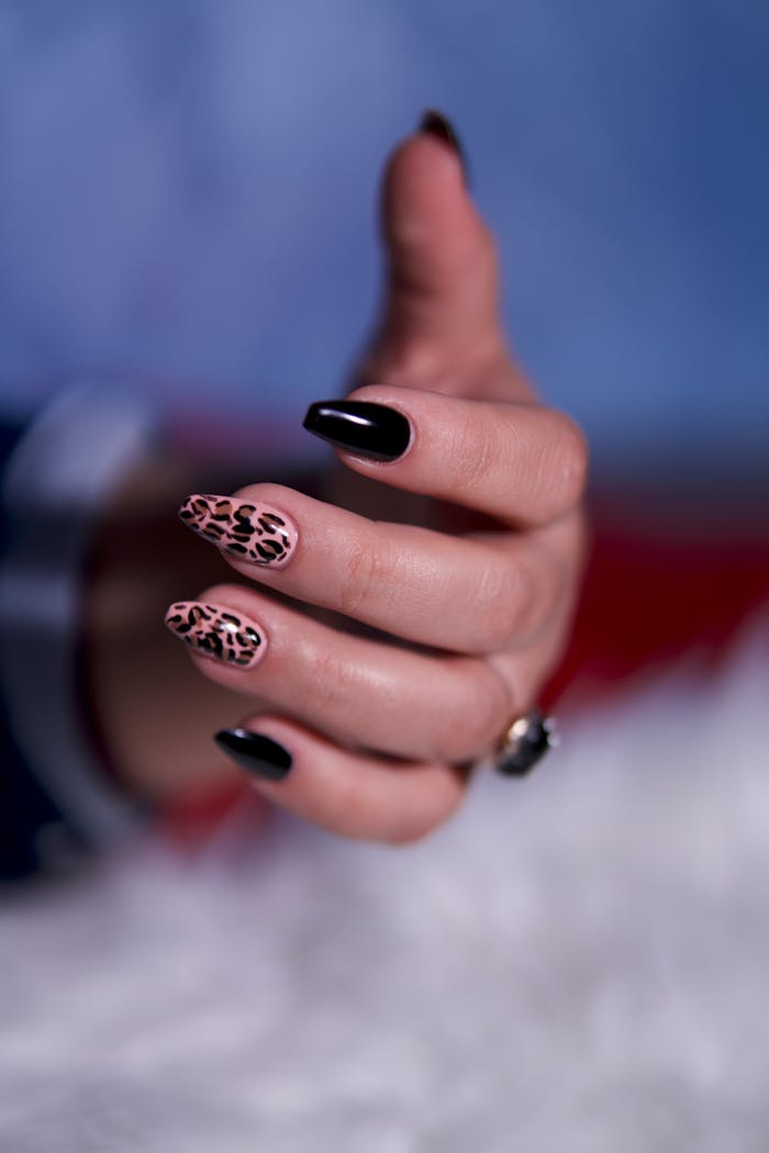 why-choose-us Close-up of a stylish hand with black and leopard print nail art.