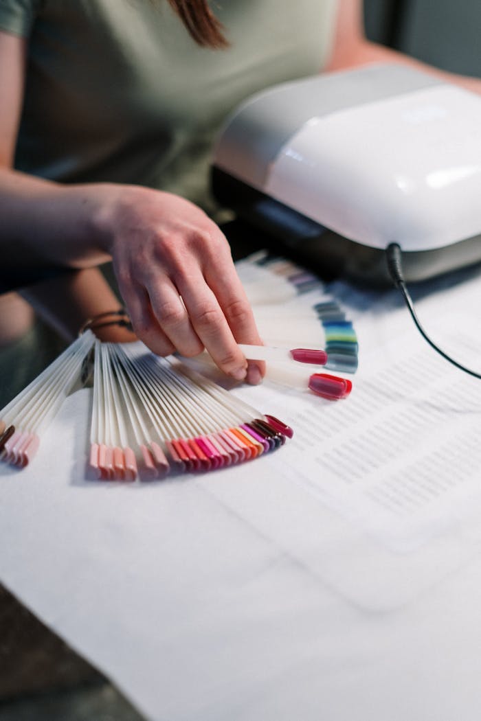 about-us Close-up of a manicurist selecting nail polish colors in a salon setting.
